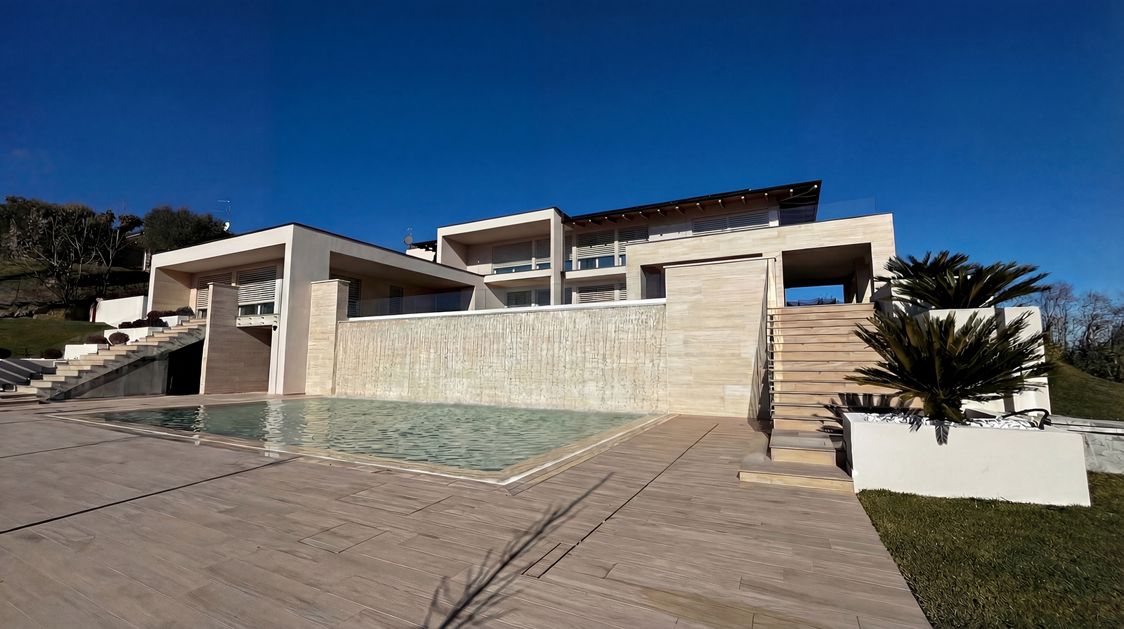 Vista esterna di Villa L|J con piscina e parete d'acqua sulla collina