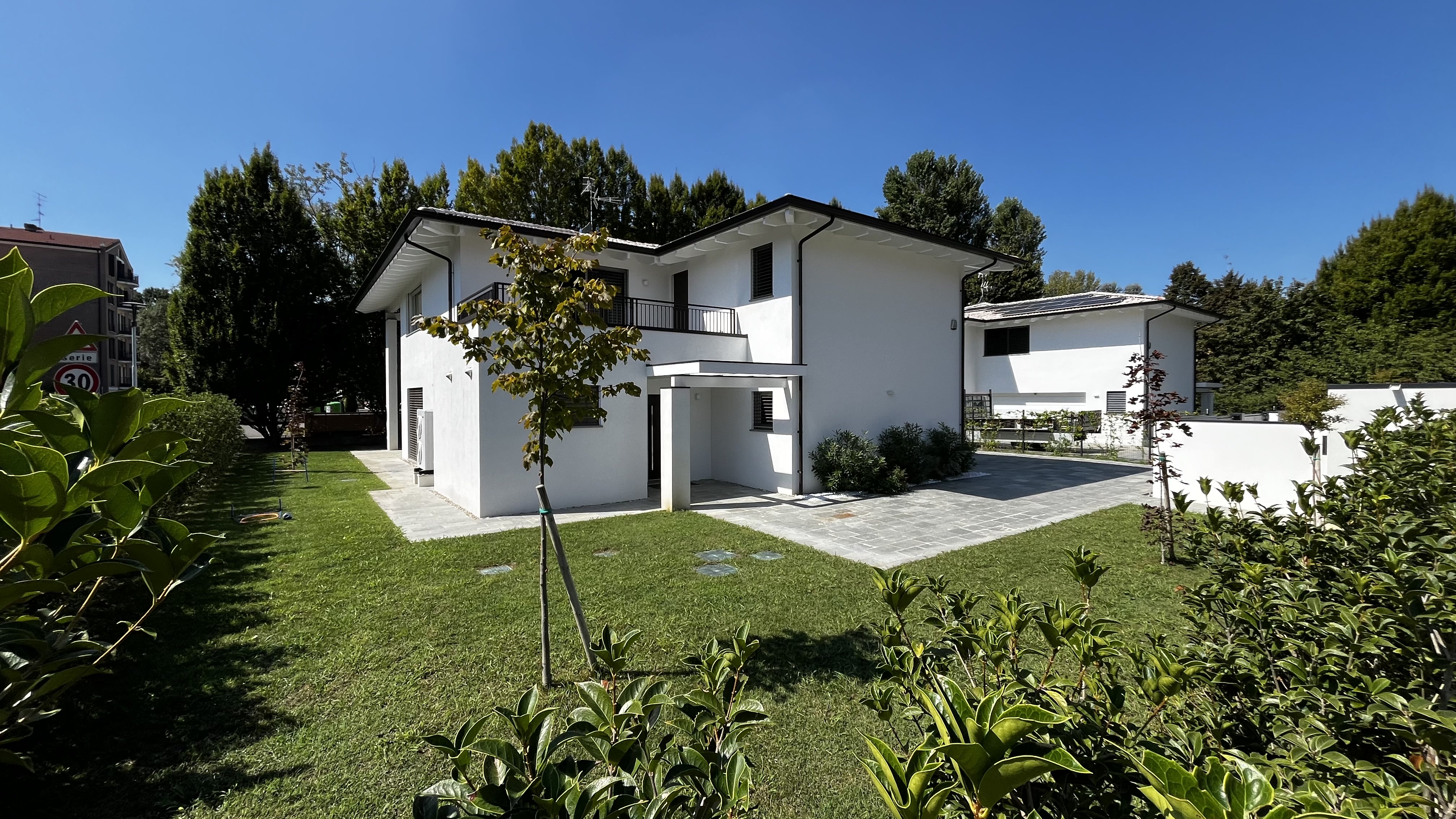 Una delle due case di Villa M|M vista dal giardino, con balcone al primo piano e patio in pietra