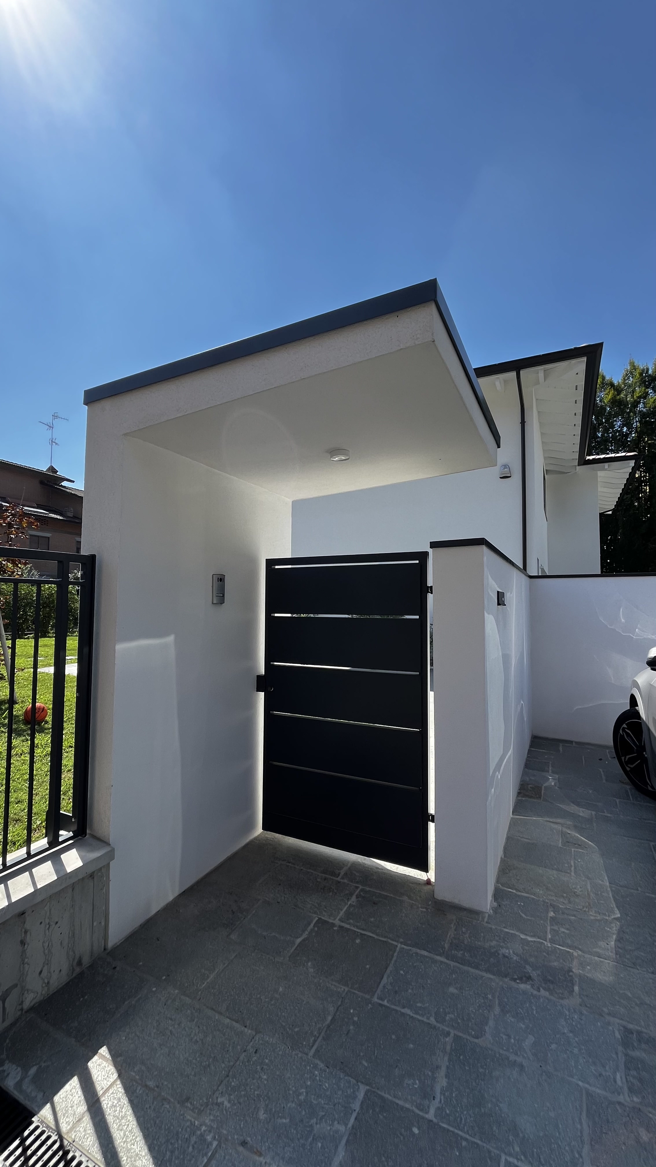 Ingresso pedonale con cancelletto nero e pensilina di una delle due abitazioni